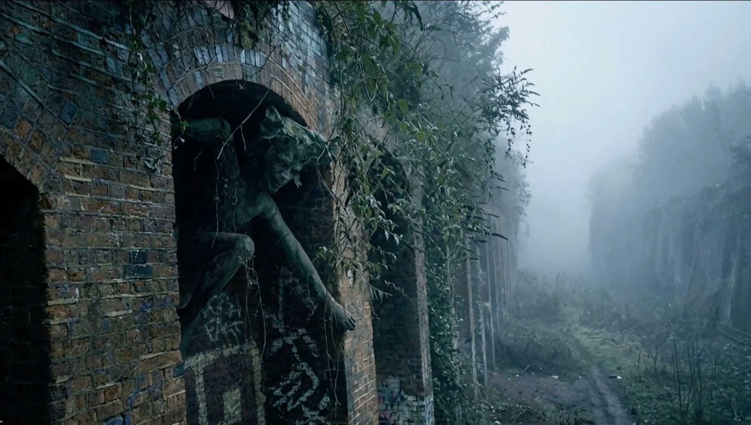 A stone figure of a horned, leaf-crowned creature leaning out of an arch in an old brick railway wall.